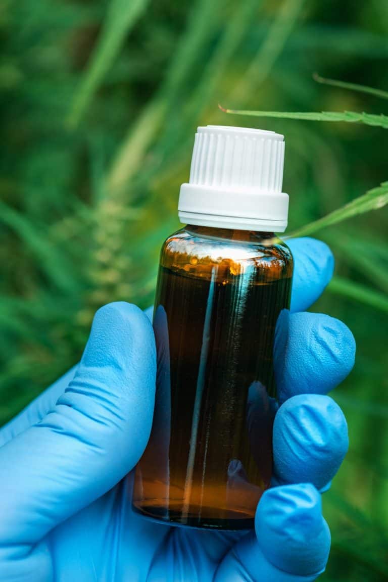 Scientist holding CBD cannabis oil bottle, close up